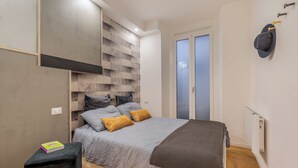 Un dormitorio moderno con una cama, un pequeño reposapiés negro y un libro encima.