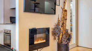 Una sala de estar moderna con chimenea, un televisor de pantalla plana en la pared y una escultura de árbol decorativa.