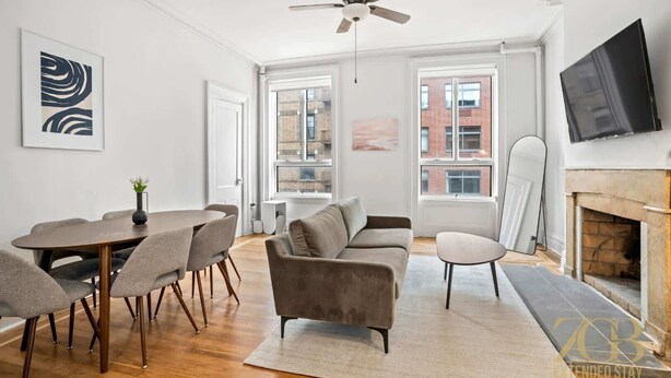 A modern living room with a dining area, a fireplace, and large windows. - Sun-Filled Brownstone Apt in Prime Chelsea (New York)