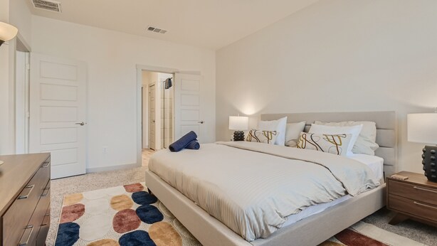 Een slaapkamer met een bed, nachtkastjes, een plafondventilator en een kamerbreed tapijt met dessin.