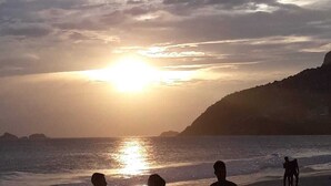 A beach scene with people and a dog at sunset. - Your best spot in Ipanema, just steps from the sea and the lagoon. (Rio de Janeiro)
