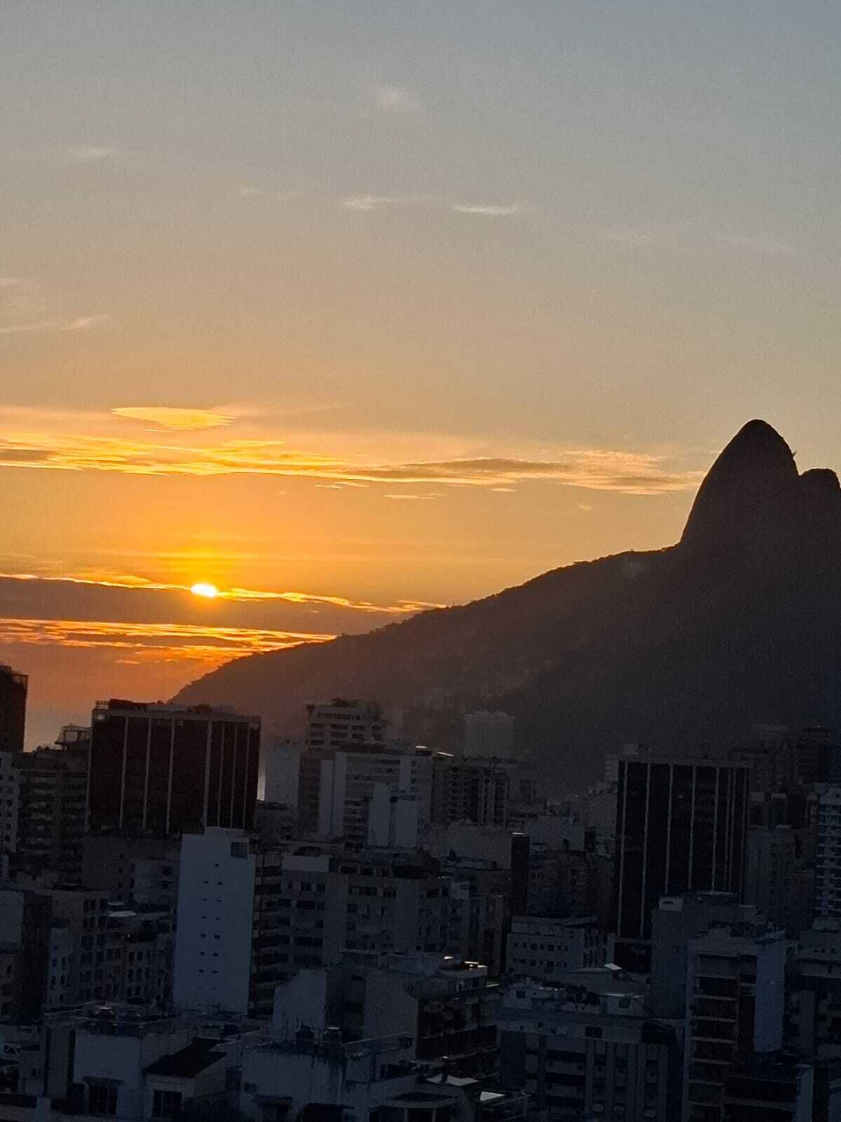 Un paisaje urbano al atardecer con la silueta destacada de una montaña.