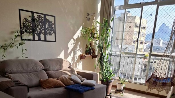 A living room with a sofa, a coffee table, and a large window with a view of buildings. - Your best spot in Ipanema, just steps from the sea and the lagoon. (Rio de Janeiro)