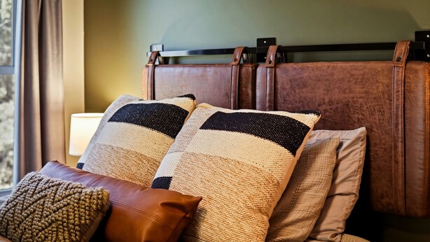 A bed with a headboard, multiple pillows, and a lamp. - Newly Refreshed : Knotty Pine Cabin + Hot Tub (Logan)