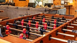 A foosball table in a room with wooden walls and a sofa. - Newly Refreshed : Knotty Pine Cabin + Hot Tub (Logan)