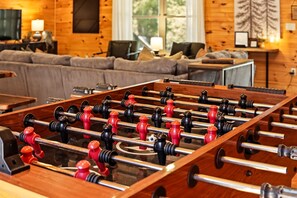 A foosball table in a room with wooden walls and a sofa. - Newly Refreshed : Knotty Pine Cabin + Hot Tub (Logan)
