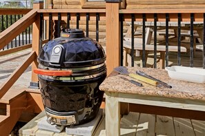 A black barbecue grill with a control panel, a red handle, and a spatula on a wooden deck. - Newly Refreshed : Knotty Pine Cabin + Hot Tub (Logan)