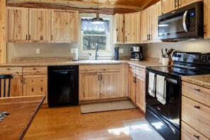 A kitchen with wooden cabinets, a microwave, a dishwasher, and a stove. - Newly Refreshed : Knotty Pine Cabin + Hot Tub (Logan)