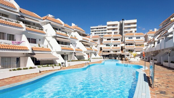 A swimming pool surrounded by multi-story buildings with terracotta roofs and white walls. - Home2Book Relax & Enjoy in Las Americas (Playa de la Américas)