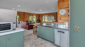 Une cuisine moderne avec des meubles de couleur turquoise, un four à micro-ondes et un lave-vaisselle. On y trouve également un coin repas en bois avec un canapé et une plante.