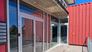 Ein modernes Gebäude mit großen Glasüren und einer roten Außenwand.