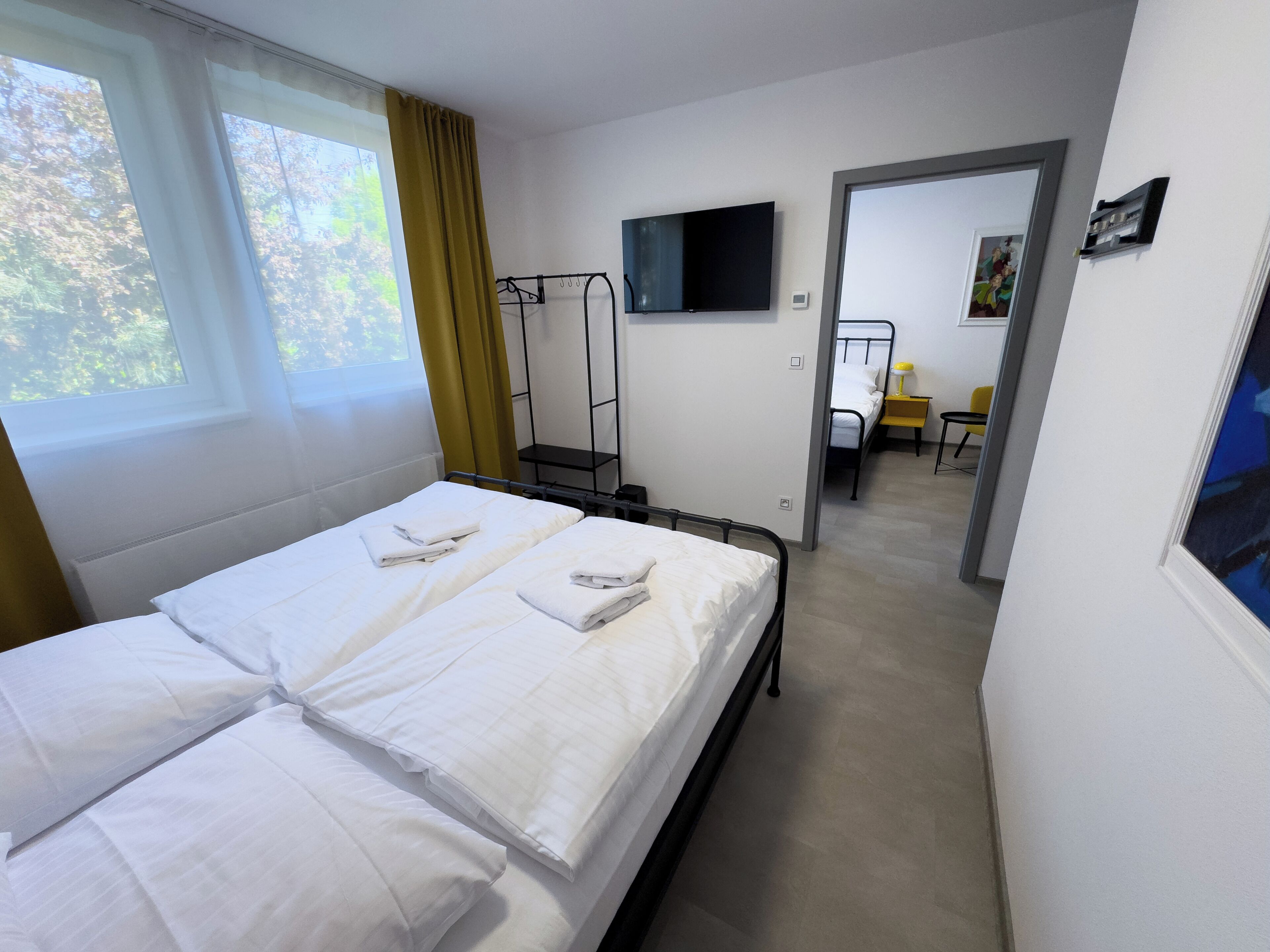 A hotel room with two beds, a TV, a desk, and a chair.