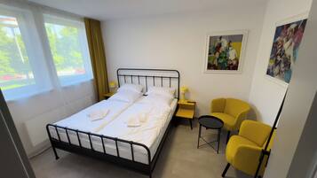 Een hotelkamer met een bed, een tafeltje, twee stoelen en kunstwerken aan de muur.