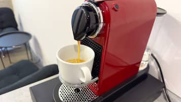 Una máquina de espresso roja sirviendo café en una taza blanca.