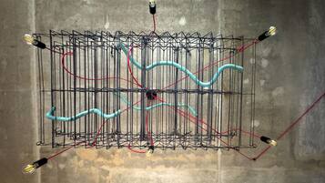 Una estructura metálica con cables y bombillas frente a un muro de concreto.