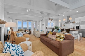 A spacious living area with a large brown sofa, wicker chairs, and a view of the ocean. - Beachfront | Hot Tub | Sleeps 12 (Port Bolivar)