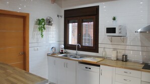Een moderne keuken met witte kastjes, een houten aanrecht, een ingebouwde magnetron en een raam met uitzicht.
