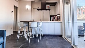 A modern kitchen with a dining area, large windows, and a view of buildings. - Saxony, close to the Center and the Sea Cozy new apartment (Fano)