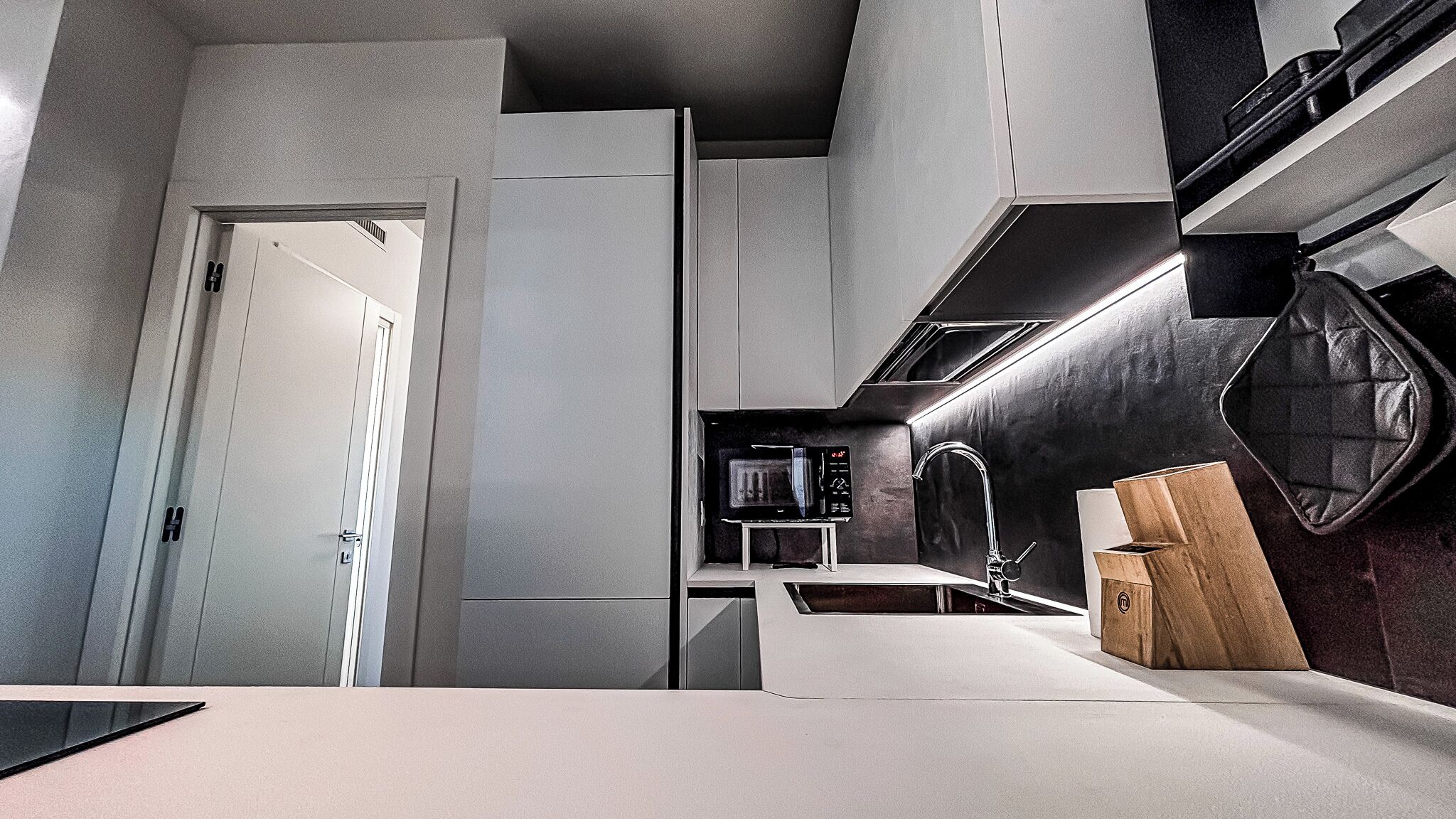 A modern kitchen with a built-in microwave, a sink, and a wooden cutting board.