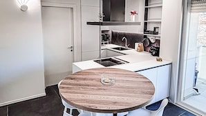 A modern kitchen with a central island, white bar stools, and a round table. - Saxony, close to the Center and the Sea Cozy new apartment (Fano)