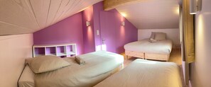 Ein Schlafzimmer mit zwei Betten, einem Holz-Kopfteil und einer violetten Akzentwand.