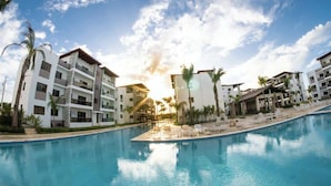 Et moderne hotel med swimmingpool, flere altaner og palmer.