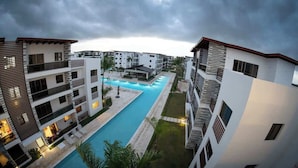 Et moderne boligkompleks med en central swimmingpool, flere altaner og en velholdt græsplæne.