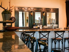 A bar area with a long counter, multiple taps, and a large mirror.