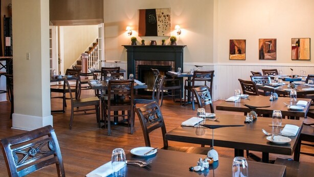 A restaurant with multiple tables and chairs, a fireplace, and wall art.