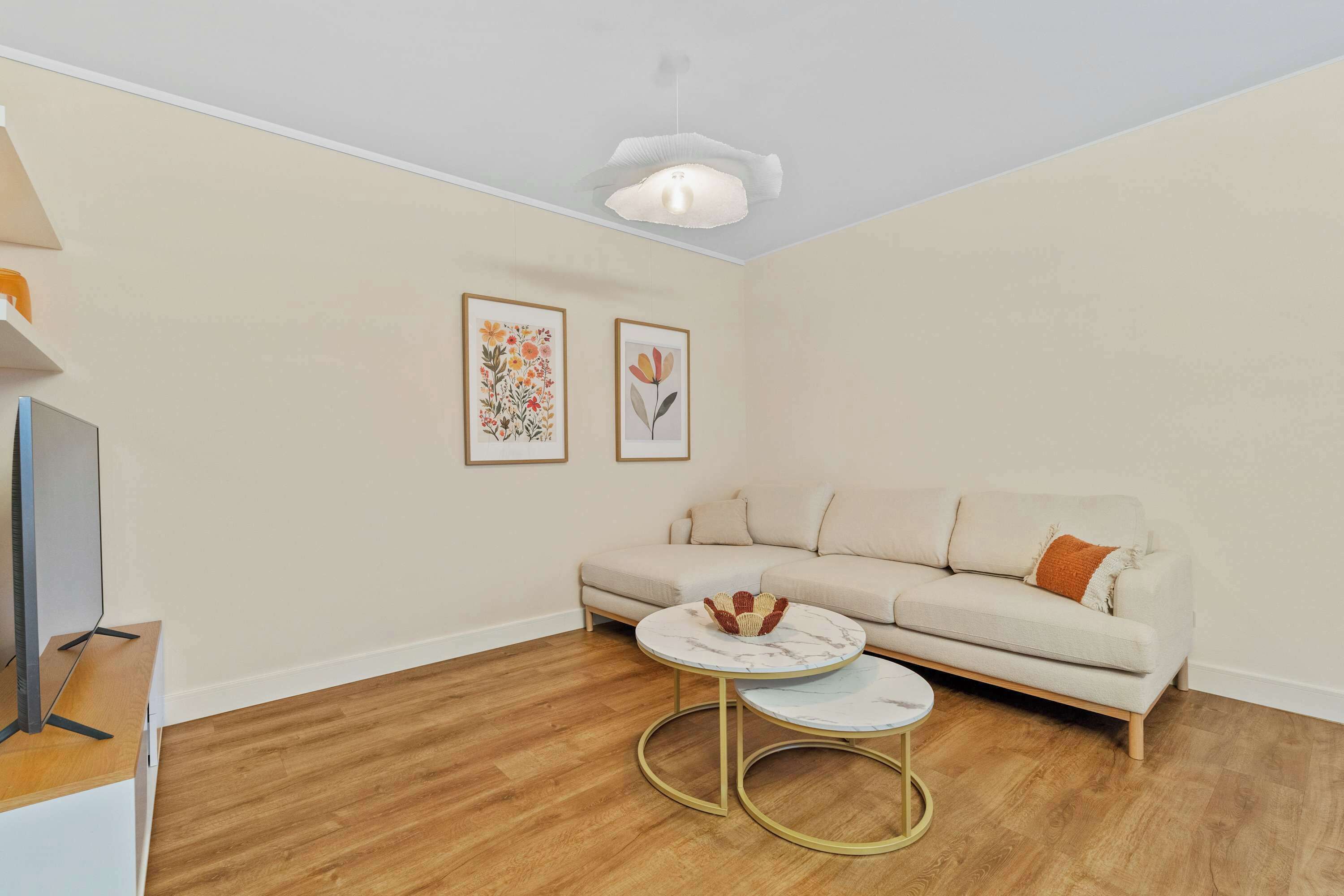 A living room with a sofa, a coffee table, and two framed artworks on the wall.