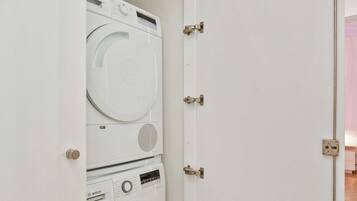 Uma lavanderia compacta com duas máquinas de lavar empilhadas e uma porta.