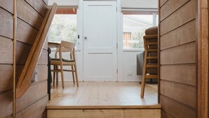 A wooden interior with a white door, a wooden chair, a wooden table, and a wooden ladder. - The Chance - Immerse yourself in the oceanic ambience of South Beach. (Port Fairy)