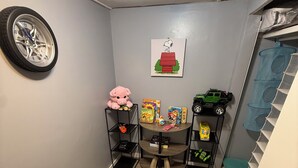 A room with a tiled floor, a wall clock, a Snoopy poster, and shelves with toys and books. - 
Welcome to the your budget friendly  stop right off the highway 27. (Somerset)