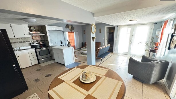A modern kitchen with white cabinets and stainless steel appliances, a dining area with a round table and chairs, and a living room with a sofa and a coffee table. - 
Welcome to the your budget friendly  stop right off the highway 27. (Somerset)