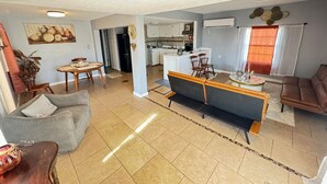 A spacious living area with a sofa, a coffee table, and a dining table. There is a kitchen in the background with cabinets and a refrigerator. - 
Welcome to the your budget friendly  stop right off the highway 27. (Somerset)