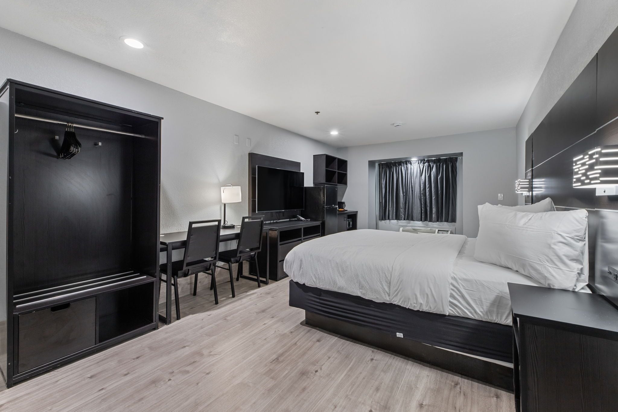A modern bedroom with a bed, desk, chair, and wardrobe.