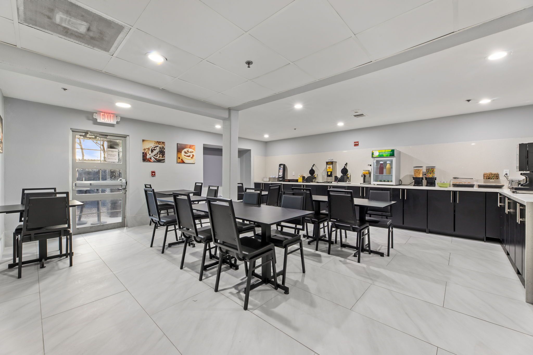 A modern kitchen area with a counter, chairs, and a refrigerator.