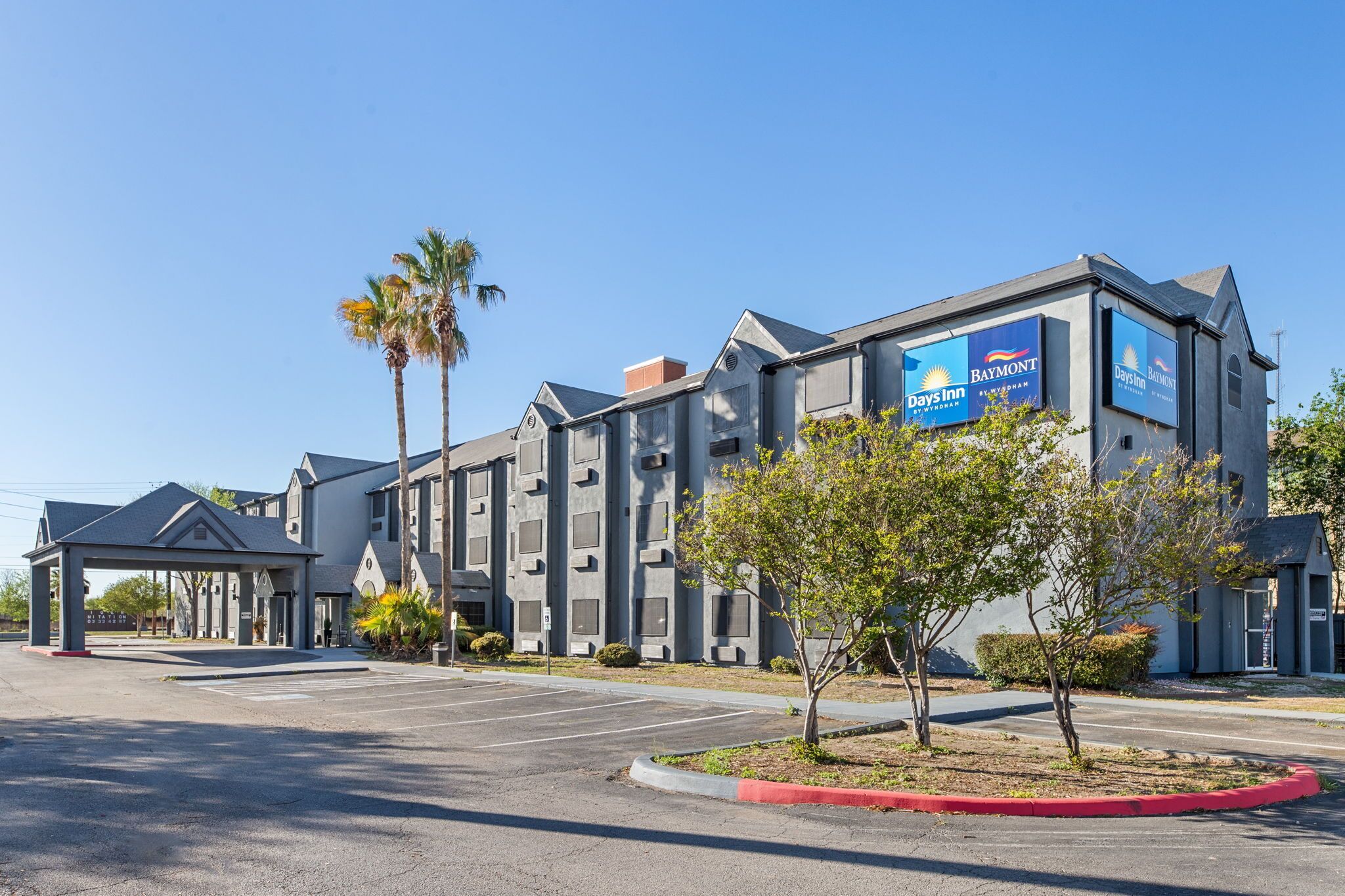 Un hotel con un letrero de Days Inn, un acceso cubierto y un estacionamiento.