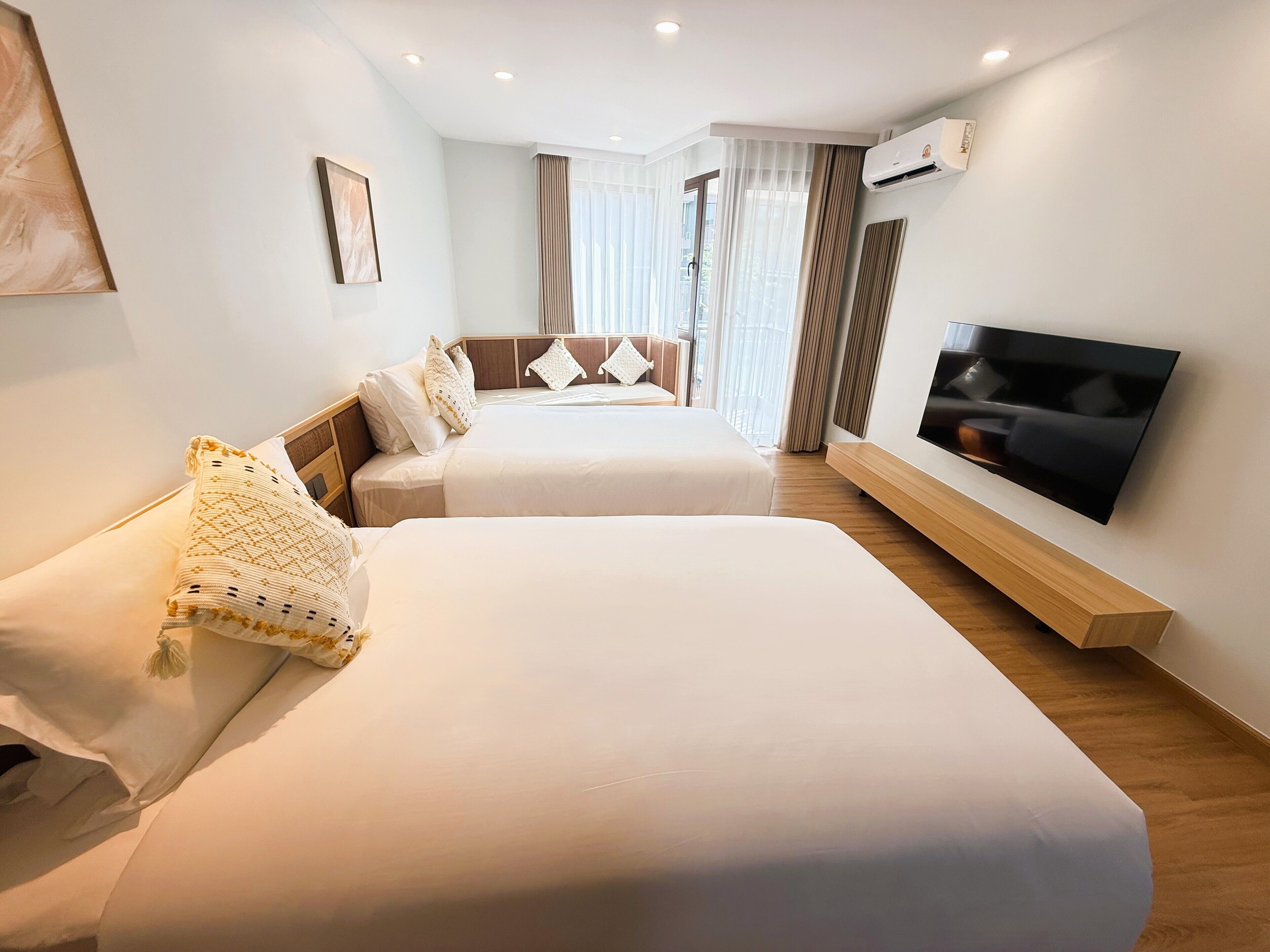 A hotel room with two beds, a TV, and an air conditioning unit.