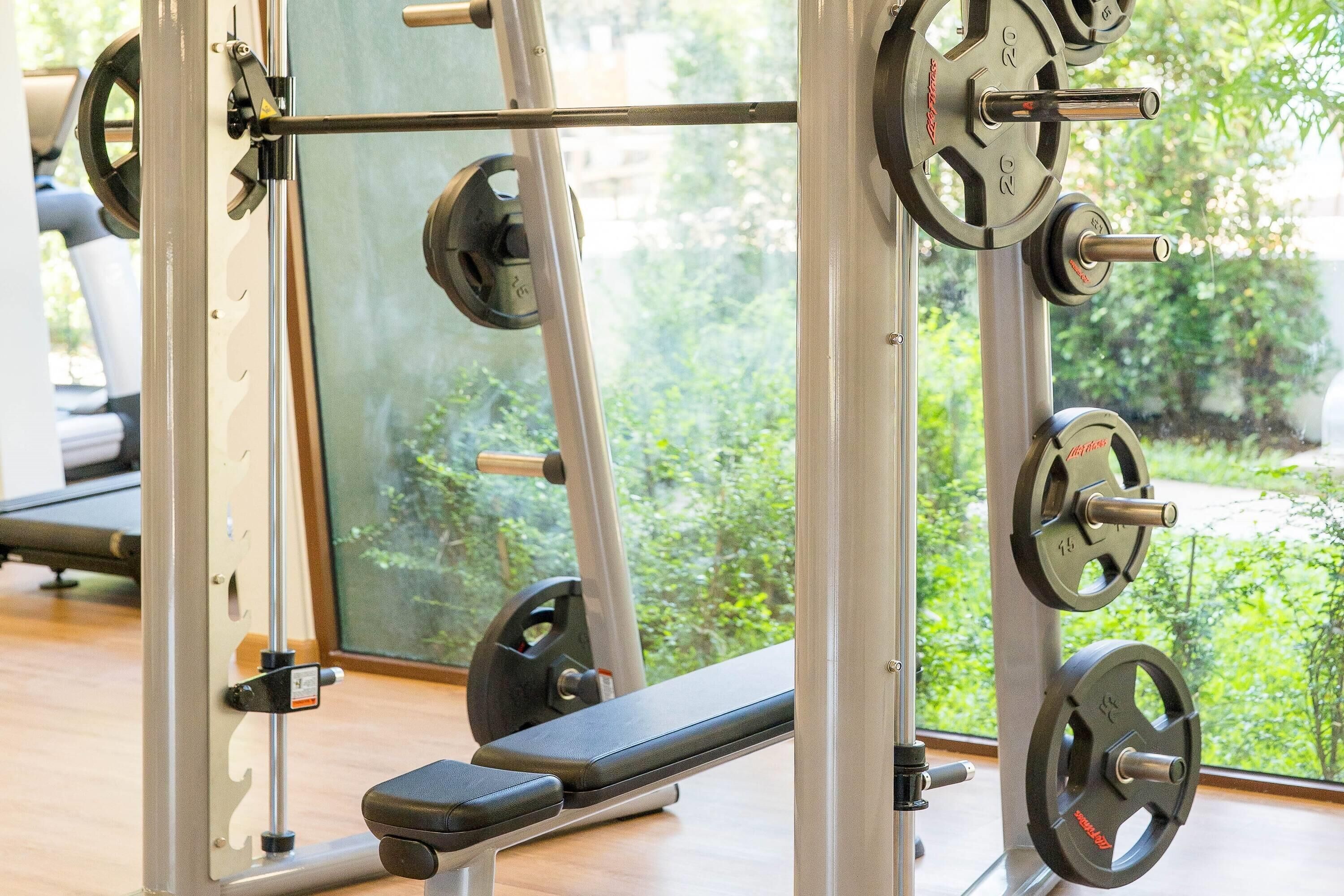 Un gimnasio con equipo de levantamiento de pesas y una banca.