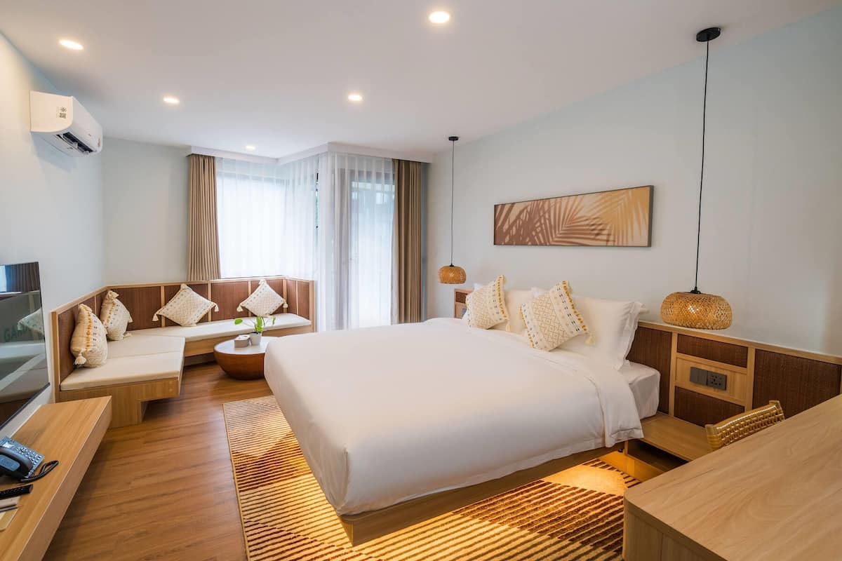 Una habitación de hotel moderna con una cama grande, un sofá, un escritorio y un televisor.