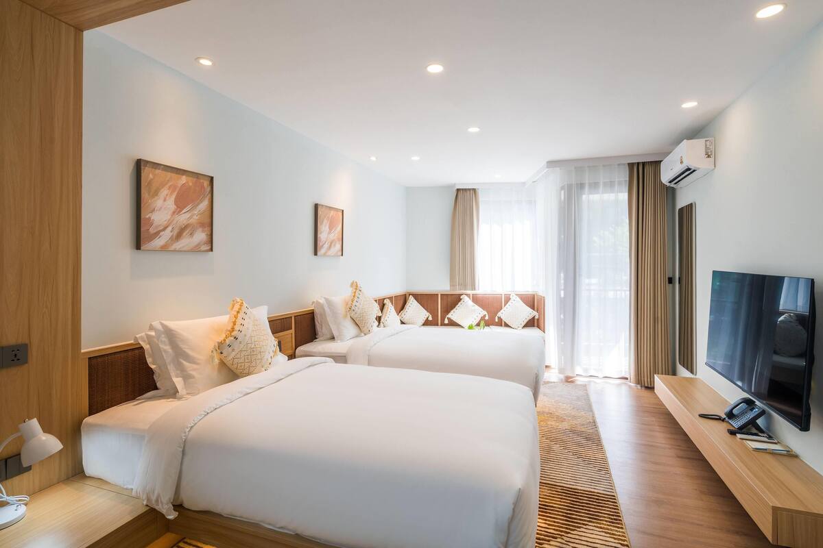 Habitación de hotel con dos camas, un televisor y un escritorio con lámpara.