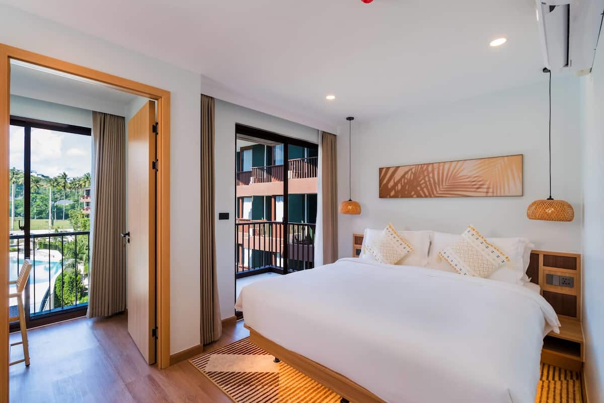 Habitación de hotel moderna con una cama grande, vistas a un balcón y una piscina.