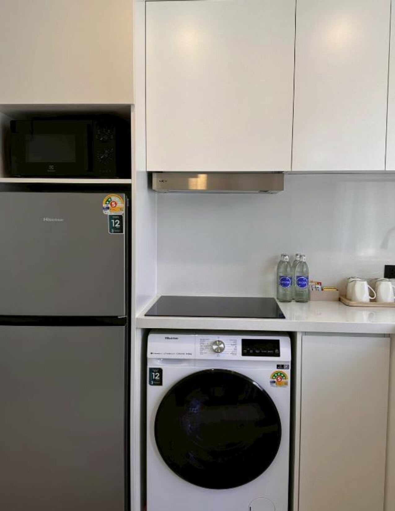 A compact kitchen with a refrigerator, microwave, and washing machine.