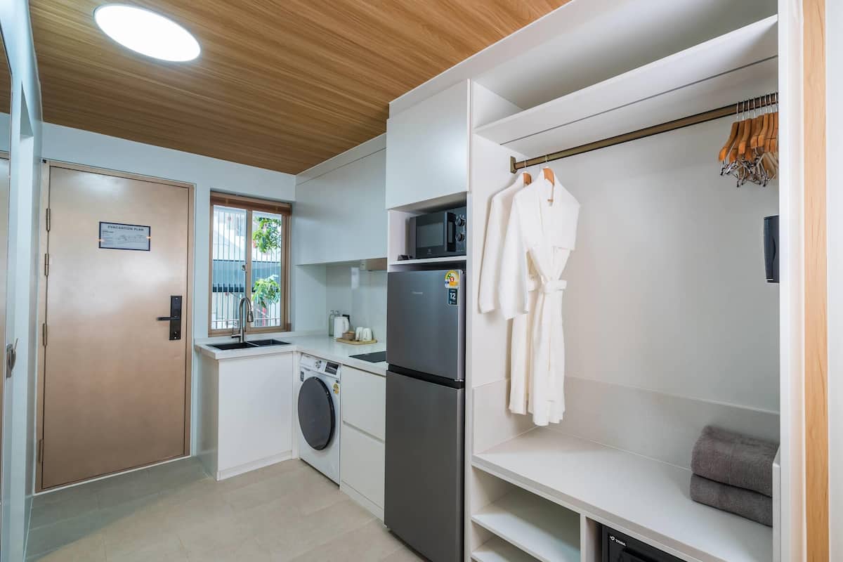 Cocina compacta con lavadora, refrigerador y tendedero.