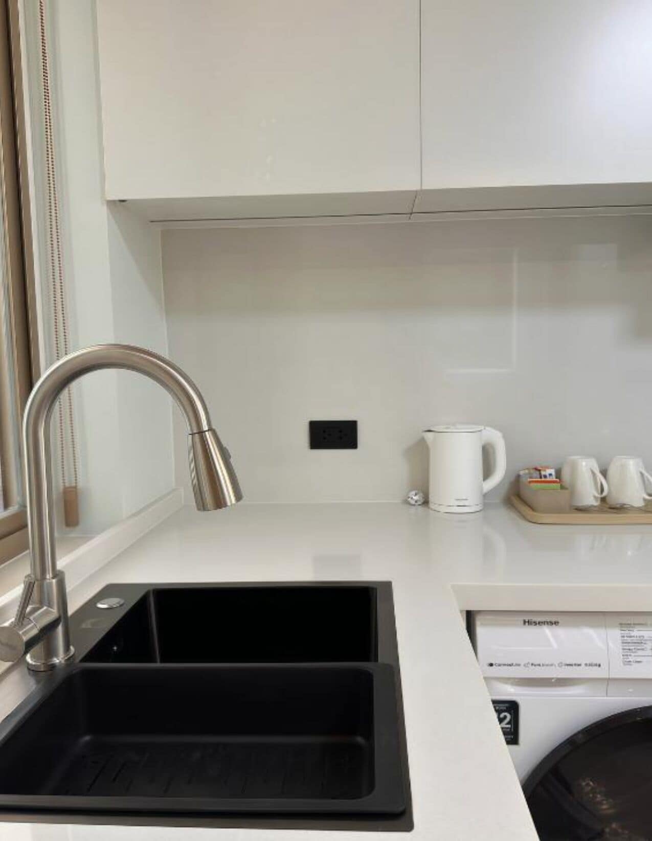 A modern kitchen with a stainless steel sink, a coffee maker, and a dishwasher.
