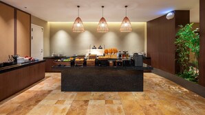 Une cuisine moderne dotée d’un îlot central, de luminaires suspendus et offrant une vue sur un jardin.