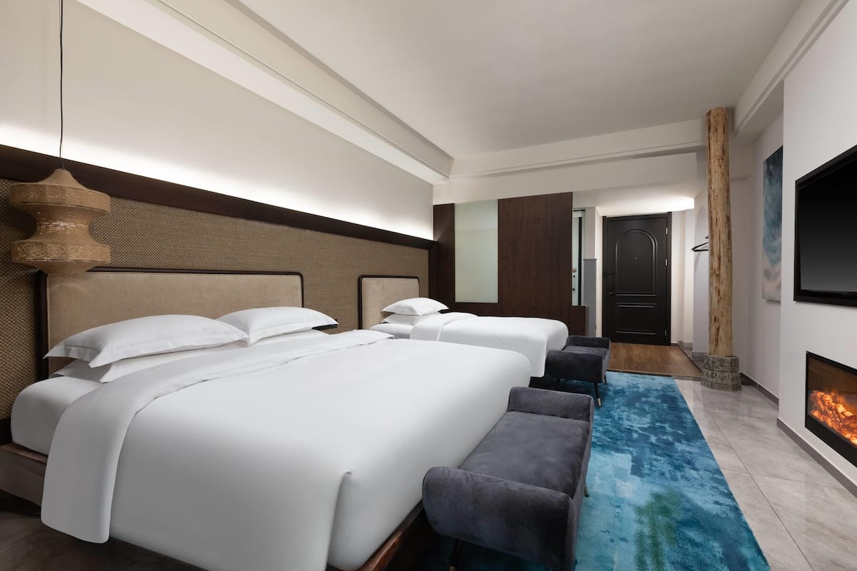 Habitación de hotel con una cama grande, televisión, chimenea y alfombra azul.