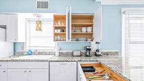 A modern kitchen with white cabinets, a granite countertop, a dishwasher, a coffee maker, and a built-in oven.
