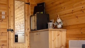 A wooden interior with a door, a cabinet, a radiator, and a small trash bin. - Livi Family Pod - hot tub (Thirsk)